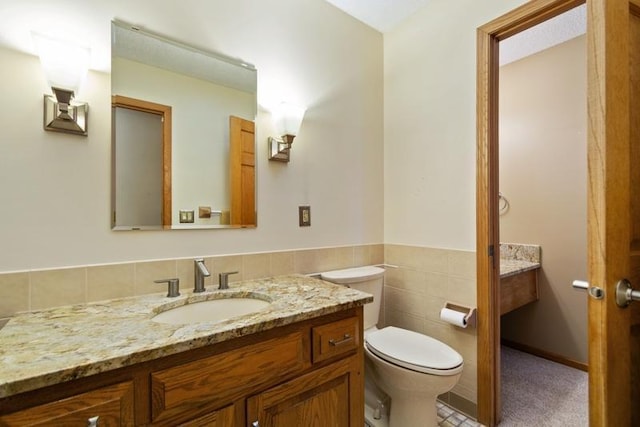 bathroom featuring tile walls, vanity, and toilet