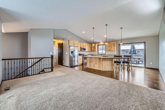 kitchen with dark colored carpet, stainless steel appliances, decorative backsplash, hanging light fixtures, and a kitchen island