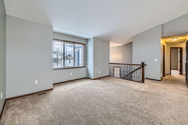 carpeted empty room with a textured ceiling