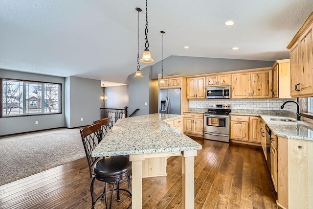 kitchen featuring light stone countertops, appliances with stainless steel finishes, a center island, tasteful backsplash, and sink