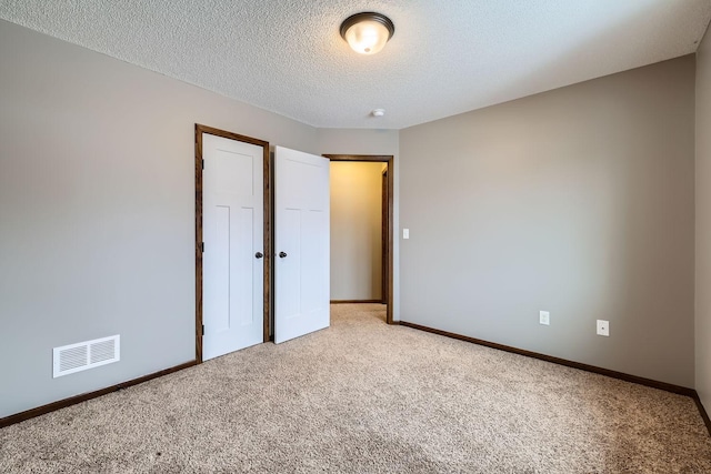 unfurnished bedroom featuring light carpet, a closet, and a textured ceiling