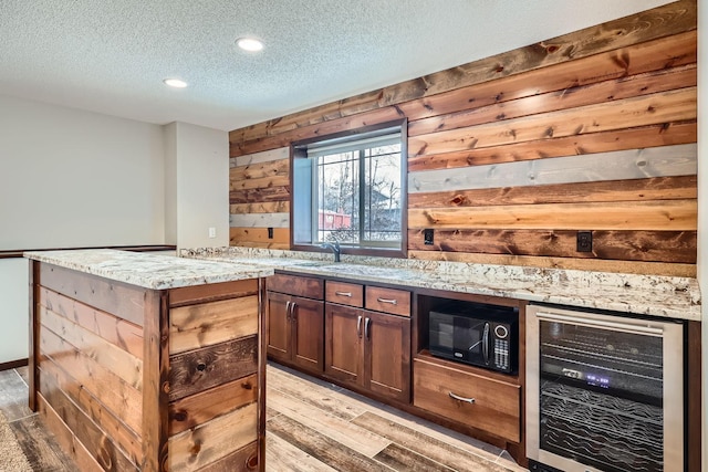 bar featuring light stone countertops, a textured ceiling, wooden walls, and wine cooler