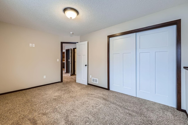 unfurnished bedroom with a textured ceiling, a closet, and light colored carpet