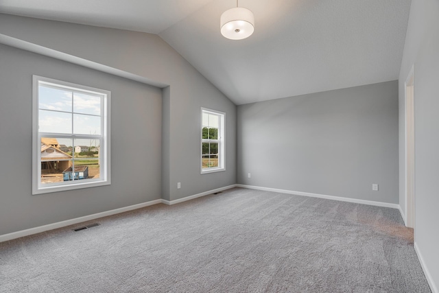 carpeted spare room with vaulted ceiling and a healthy amount of sunlight