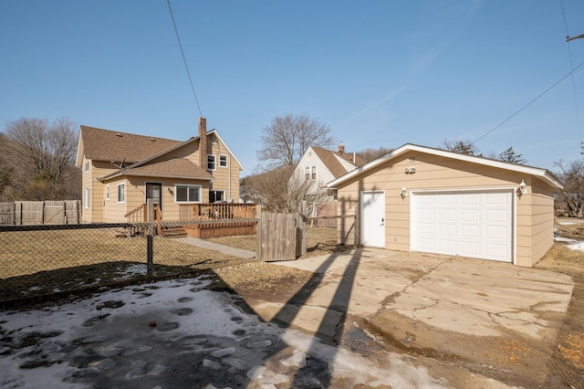 view of front facade with an outbuilding, concrete driveway, a detached garage, and fence