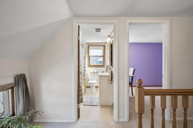 hallway featuring baseboards, visible vents, carpet floors, and lofted ceiling