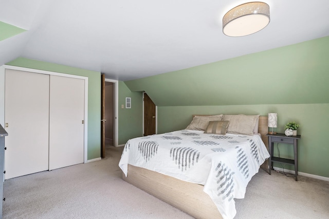 bedroom with a closet, baseboards, carpet, and vaulted ceiling