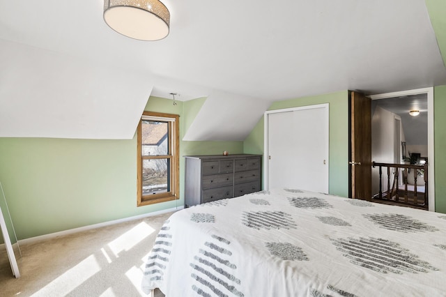 carpeted bedroom featuring a closet, baseboards, and lofted ceiling