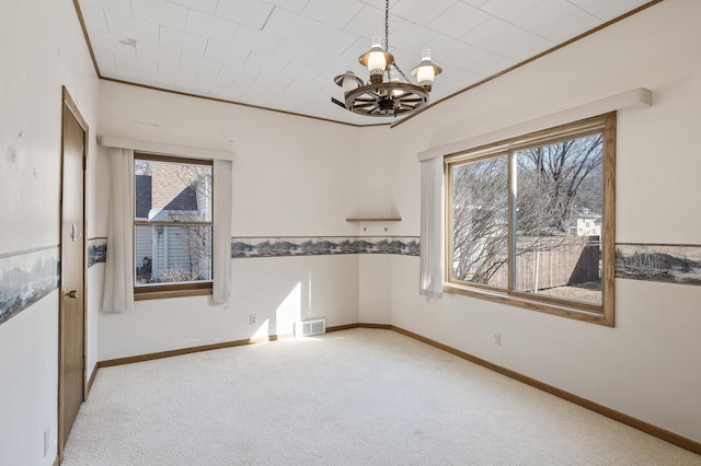 empty room with a notable chandelier, ornamental molding, baseboards, and carpet floors