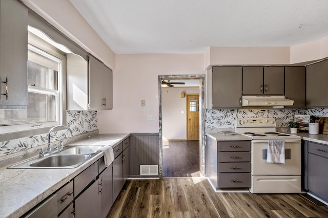 kitchen featuring visible vents, white range with electric cooktop, under cabinet range hood, dark wood-style floors, and a sink