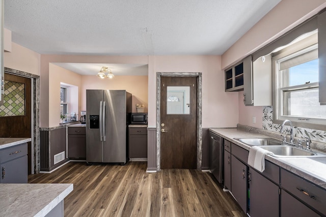 kitchen featuring visible vents, dark wood-type flooring, a sink, appliances with stainless steel finishes, and light countertops