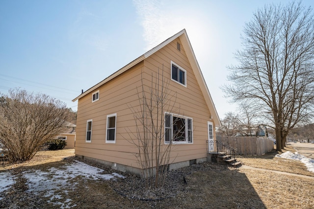 view of side of home featuring crawl space and fence