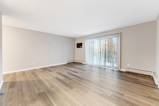 unfurnished room featuring baseboard heating and light wood-type flooring