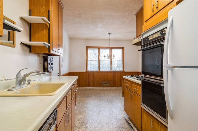 kitchen featuring wooden walls, decorative light fixtures, white appliances, a textured ceiling, and sink