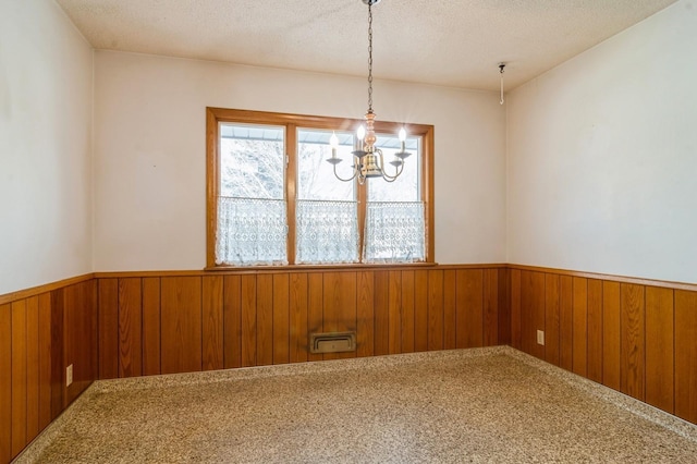 carpeted spare room featuring an inviting chandelier and a textured ceiling