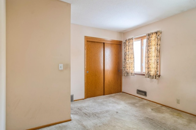 unfurnished bedroom featuring light colored carpet and a closet