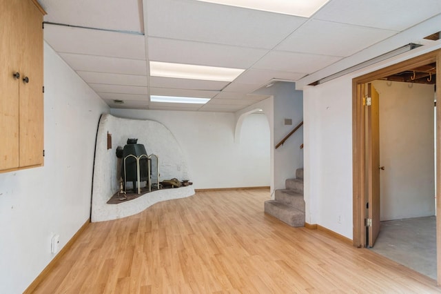 basement with a paneled ceiling and light hardwood / wood-style flooring