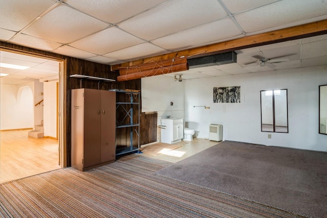 basement with ceiling fan, a paneled ceiling, and carpet