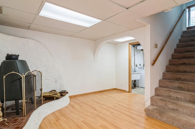 basement featuring washer / dryer, a paneled ceiling, and wood-type flooring