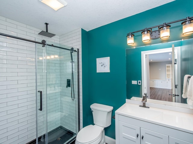 bathroom featuring a textured ceiling, toilet, walk in shower, and vanity