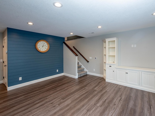 interior space featuring dark wood-type flooring, a textured ceiling, and wooden walls