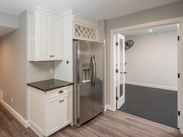 kitchen featuring white cabinets, dark stone counters, stainless steel fridge with ice dispenser, and light hardwood / wood-style flooring