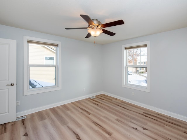 empty room with ceiling fan, light wood-type flooring, and a healthy amount of sunlight