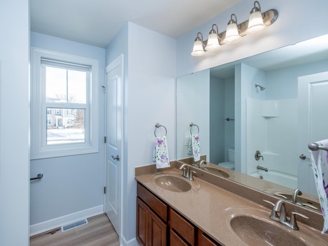 full bathroom with toilet, hardwood / wood-style flooring, vanity, and washtub / shower combination