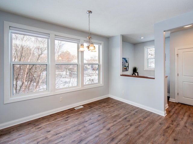 unfurnished dining area with dark wood-type flooring and an inviting chandelier