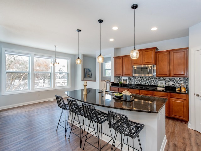 kitchen with hardwood / wood-style flooring, tasteful backsplash, a kitchen island with sink, a kitchen breakfast bar, and sink