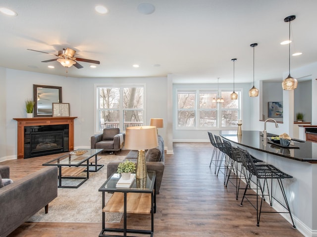 living room with ceiling fan with notable chandelier, sink, and wood-type flooring