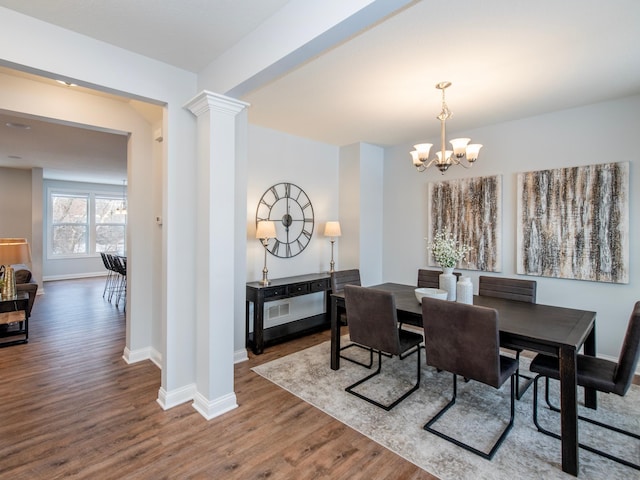 dining space featuring ornate columns, a chandelier, and hardwood / wood-style floors