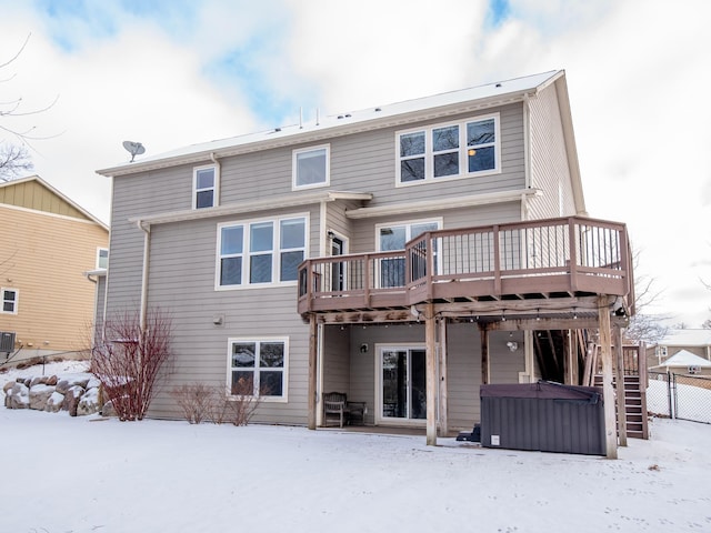 snow covered property featuring central AC unit, a hot tub, and a wooden deck