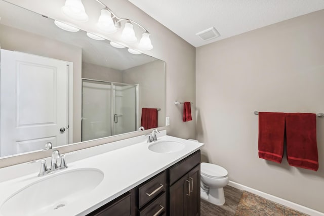 bathroom featuring a textured ceiling, vanity, hardwood / wood-style flooring, toilet, and a shower with shower door