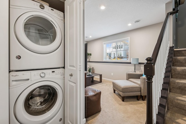 clothes washing area featuring light carpet, a textured ceiling, and stacked washer / dryer