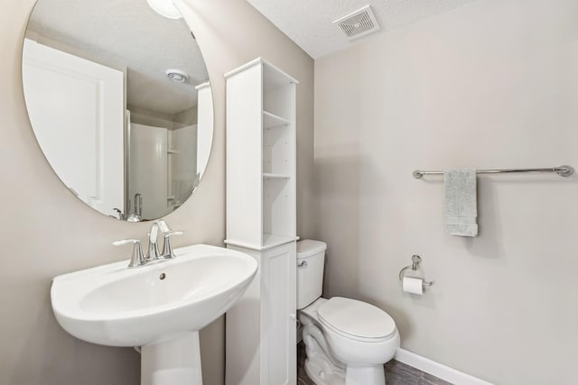 bathroom featuring toilet, sink, and a textured ceiling