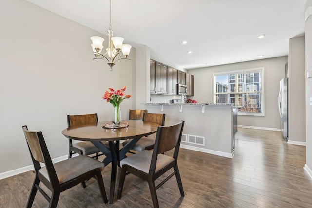 dining space with dark hardwood / wood-style flooring and a chandelier