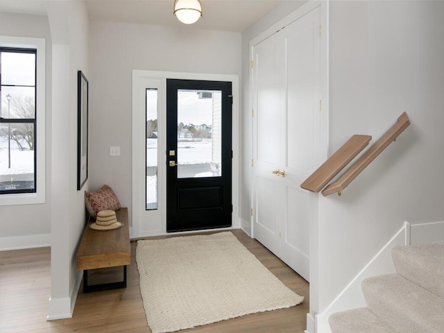 entryway with stairs, plenty of natural light, light wood-style flooring, and baseboards