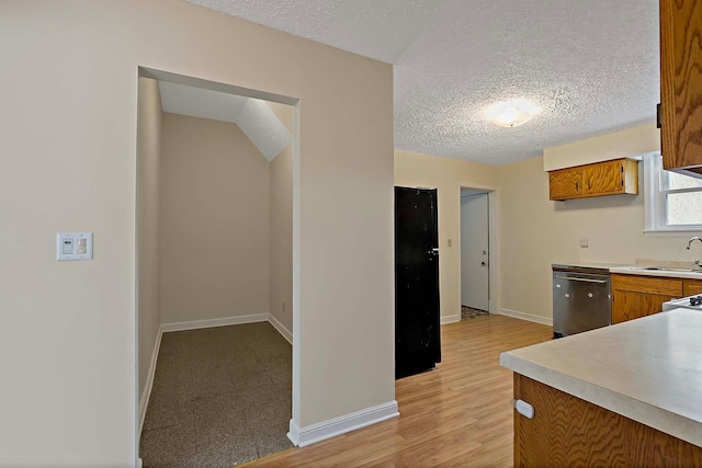 kitchen with brown cabinetry, baseboards, light countertops, and stainless steel dishwasher