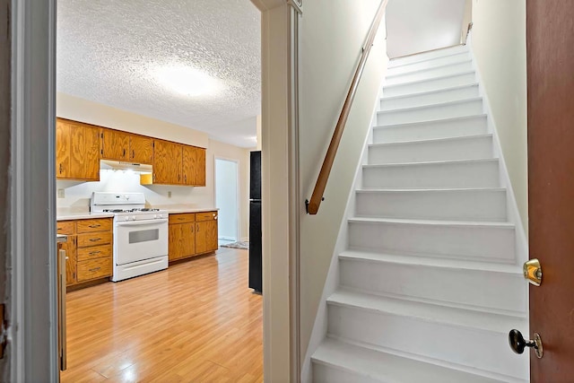 stairway with a textured ceiling and wood finished floors