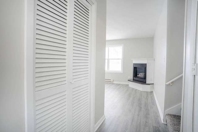 hall with a baseboard radiator and light hardwood / wood-style floors