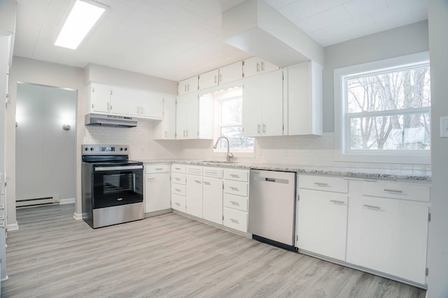 kitchen featuring sink, baseboard heating, stainless steel appliances, light stone counters, and white cabinets