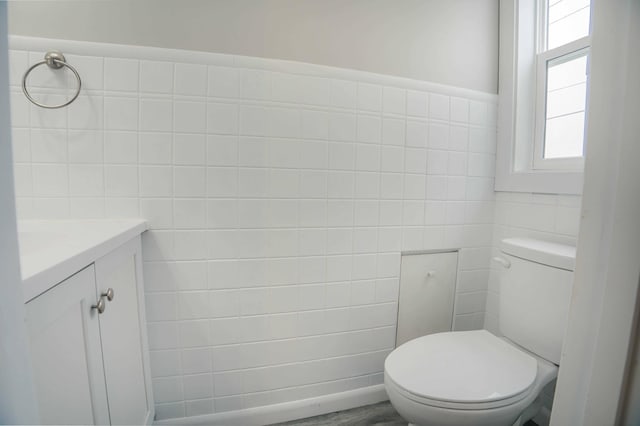 bathroom with vanity, toilet, and tile walls