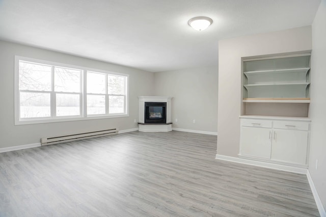 53 Eastview Dr, Hancock, MN 56244 - unfurnished living room with baseboard heating, light wood-type flooring, baseboards, and a glass covered fireplace