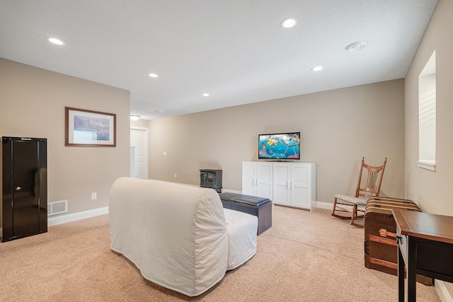 carpeted living room with a wood stove