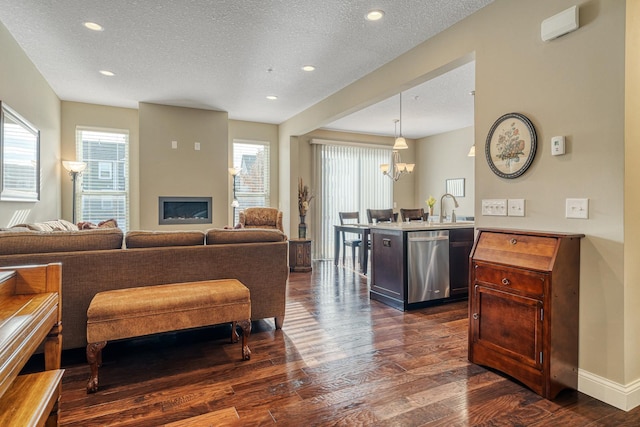 kitchen featuring hanging light fixtures, stainless steel dishwasher, dark hardwood / wood-style floors, and a textured ceiling