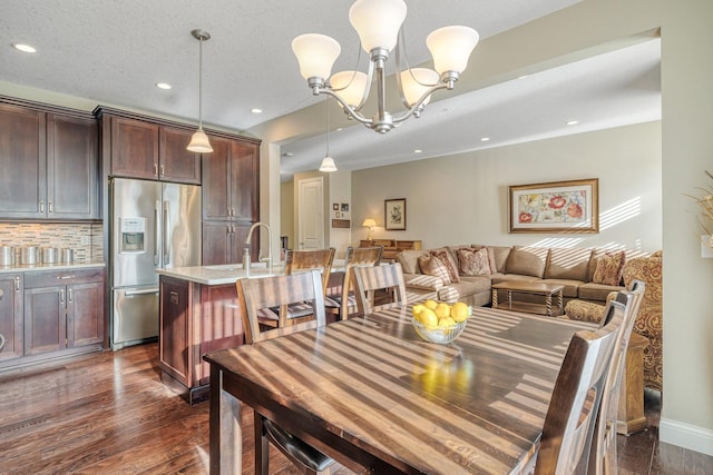 dining space featuring sink, a textured ceiling, dark hardwood / wood-style floors, and a chandelier