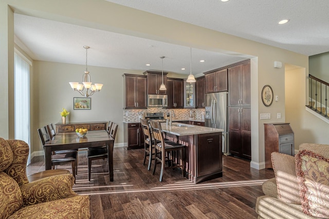 kitchen featuring hanging light fixtures, dark brown cabinets, stainless steel appliances, and a kitchen island