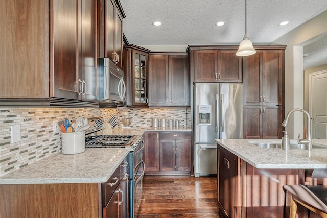 kitchen with light stone counters, appliances with stainless steel finishes, sink, and decorative backsplash