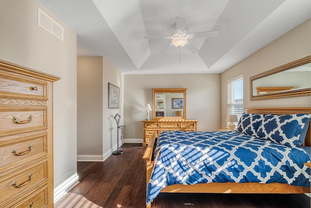 bedroom featuring ceiling fan, dark hardwood / wood-style floors, and a raised ceiling